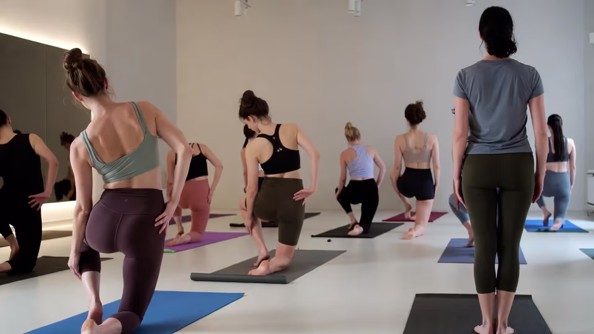 Yoga class in a studio with participants wearing leggings, bike shorts, and fitted tops.